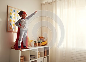 Child girl in a super hero costume with mask and red cloak