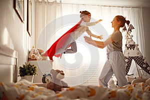 Child girl in a super hero costume with mask and red cloak