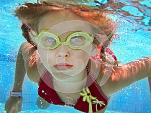 Child girl swim underwater in pool.