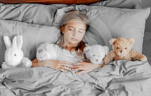 Child girl with teddy bear toy in the bed