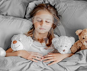 Child girl with teddy bear toy in the bed