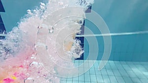 Child girl or teenager jump and swims underwater in the pool. Shooting a video underwater as a child diving and swimming