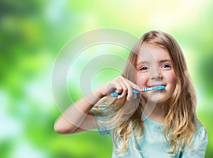 Child girl with toothbrush on green nature background. Dental ba