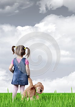 Child girl with toy bear looking into the distance, back view
