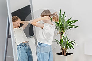 Child Girl Tying Hair in Front of Mirror. Morning preparation before school