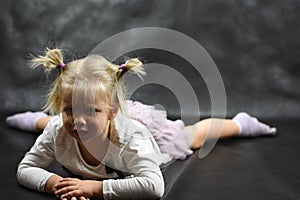 Child girl upset lying on the floor and crying on a black background