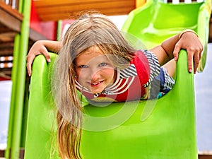 Child girl upside down on playground .