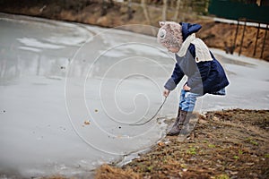 Child girl walking on frozen lake, started to melt in early spring day