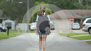 Child girl walking on rural road returning home from school