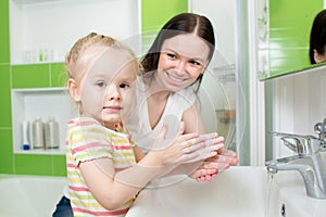 Child girl washing hands with soap in bathroom