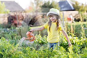 Child girl watering plants in a garden