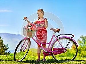 Child girl wearing sundress rides bicycle into park. photo
