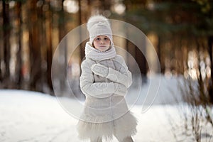 Child girl in a white jacket on the snow in a winter park, childhood and background. Frost and snowy winter, recreation for