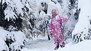 Child girl in winter playing in snow in park outdoor.