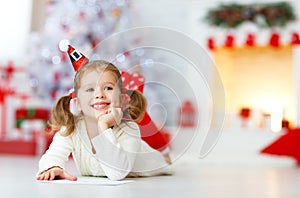 Child girl writing letter santa home near Christmas tree