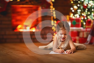 Child girl writing letter santa home near Christmas tree