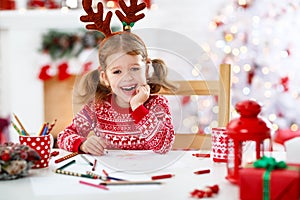 Child girl writing letter santa home near Christmas tree