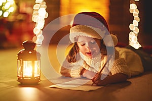 Child girl writing letter santa home near Christmas tree