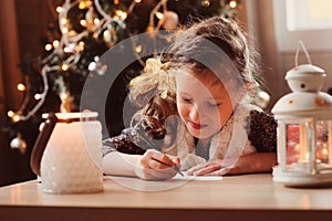 Child girl writing letter to Santa at home. 8 years old girl making gift list for Christmas or New Year at home