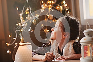 Child girl writing letter to Santa at home. 8 years old girl making gift list for Christmas or New Year at home