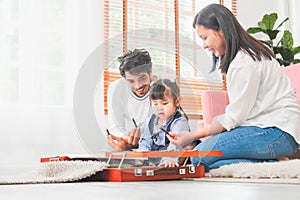 Child girl with young family having fun in the living room, Parents and daughter playing at home, Family spending time in the
