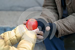 Child gives apple to the beggar