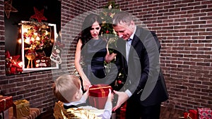 Child gives a gift to parents congratulates mother and father a happy holiday, Family New Year`s Eve, Christmas party