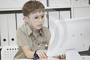 A child with glasses at the computer.