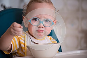 Child with glasses eating porridge