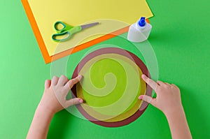 Child glues two circles with color paper, glue and scissors