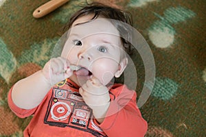 Child gnaws a bone. One-year-old baby gnaws a plastic toy because his teething. Little cheerful boy in a light green suit with