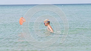 Child goes in sea with butterfly net to catch fish and crabs. Little boy playing in ocean water, kid having fun. Summer