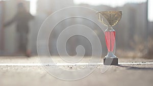 Child goes in for sports, wins trophy cup theme. Close-up of a cup on a treadmill to which a sprightly preschool child is running.