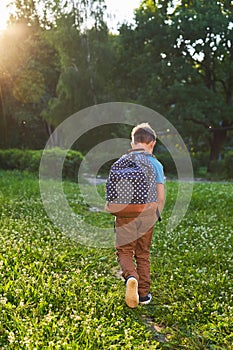 The child goes to school. boy schoolboy goes to school in the morning. happy child with a briefcase on his back and textbooks in