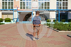 The child goes to school. boy schoolboy goes to school in the morning. happy child with a briefcase on his back and textbooks in