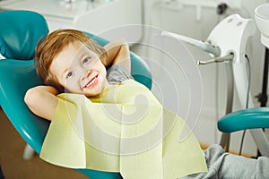 Child in good mood sitting on chair and without fear waiting dentist. Young boy is going to treat teeth. caries