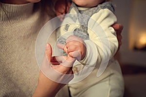 Child grabbed his mother`s finger. The mother is holding the child in her arms