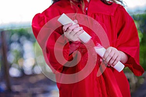 Close-up of Hands of Kindergartner in Red Graduation Gown photo
