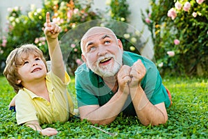 Child with Grandfather dreams in summer in nature. Happy child with Grandfather playing outdoors. Grandpa retiree
