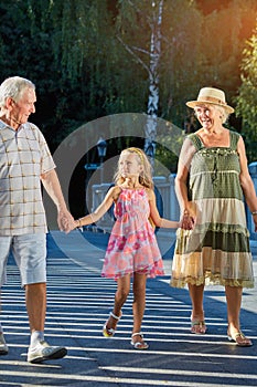 Child with grandparents walking outdoors.