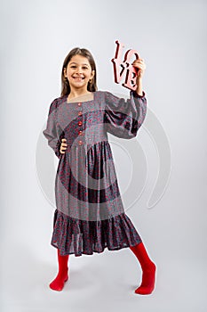 A child in a gray dress with flowers, with red buttons, in red tights, with the inscription love in her hands, isolated on a white photo