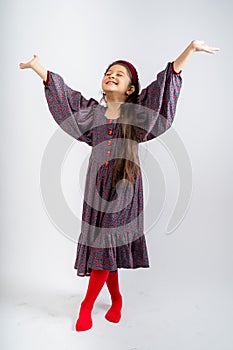 A child in a gray dress with flowers, with red buttons, in red tights, isolated on a white background.