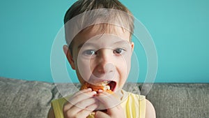 Child greedily with pleasure bites a big burger in lifestyle the kitchen at home. Kid eats fast food close-up. little