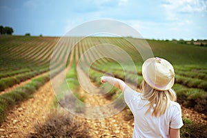 Child in green field in Provence, France pointing at something