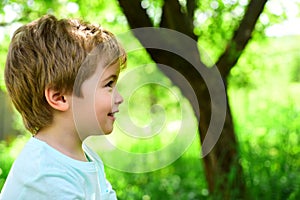 Child on green nature background. Spring and joy. Little boy looks away. Portrait. Allergy and pollinosis. Beautiful