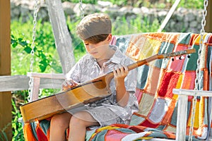 Child with guitar outdoor. Kids music and songs. Dreamy kids face. Smiling child playing outdoors in summer.