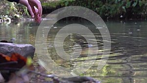 Child in gums enters a mountain river, wets his hands and shakes off water