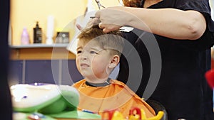 Child hairstyle. Hairdresser working with small boy in barbershop