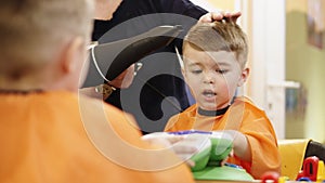 Child hairstyle. Hairdresser working with small boy in barbershop