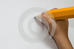 Child hand with big orange pencil